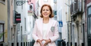 Mujer sonriente en una calle de Lisboa, vestida con traje claro.
