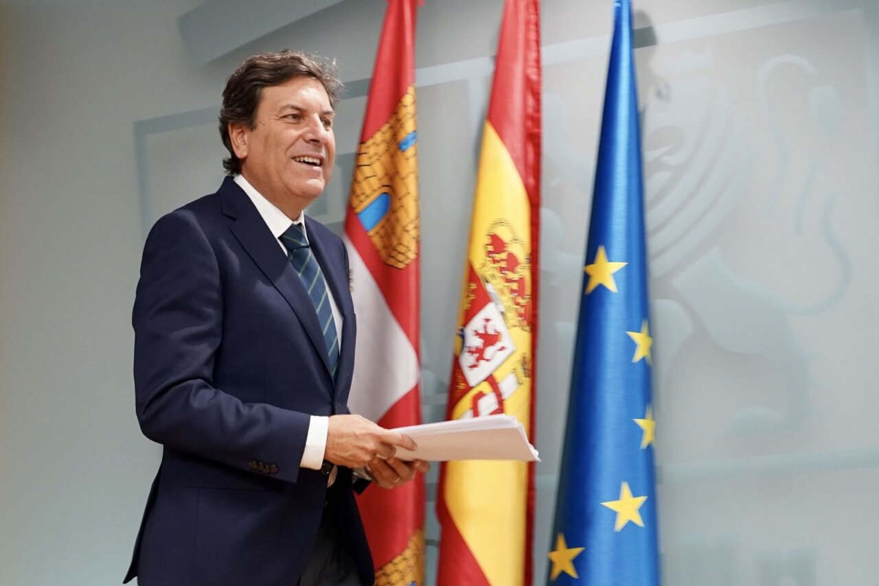 Hombre sonriente en un evento con banderas de España y Europa