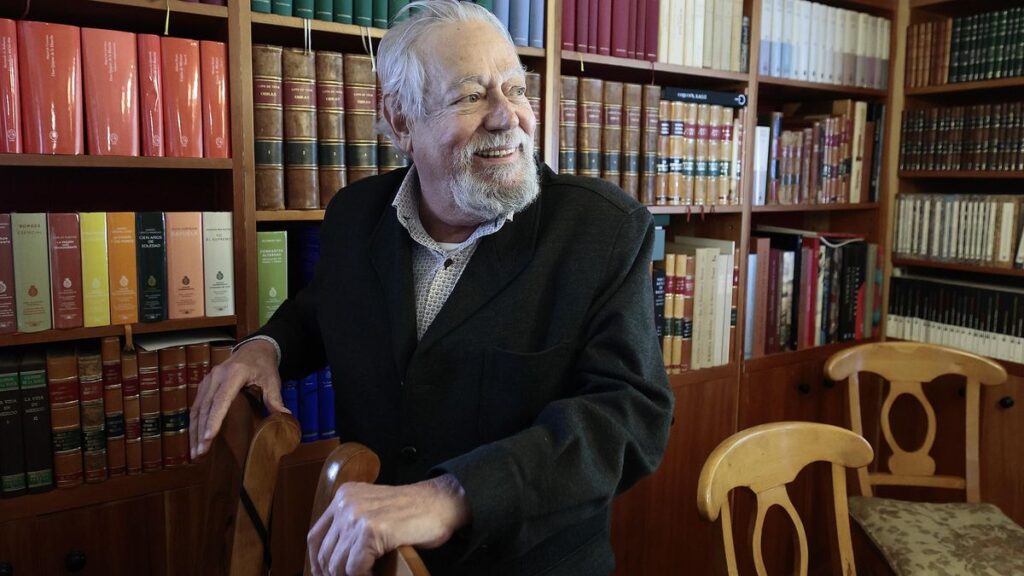 Gonzalo Celorio sonriendo en su biblioteca con libros detrás.