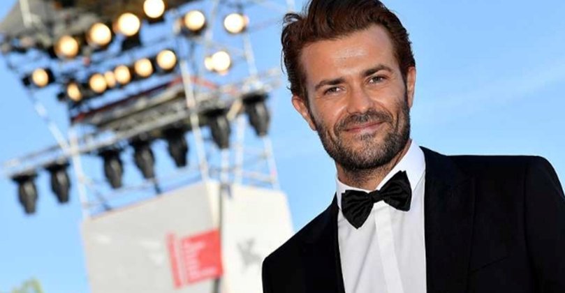 Actor en evento de premiación en Valência con luces de fondo