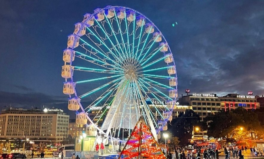 Rueda de la fortuna iluminada en Wonderland Lisboa durante la noche.