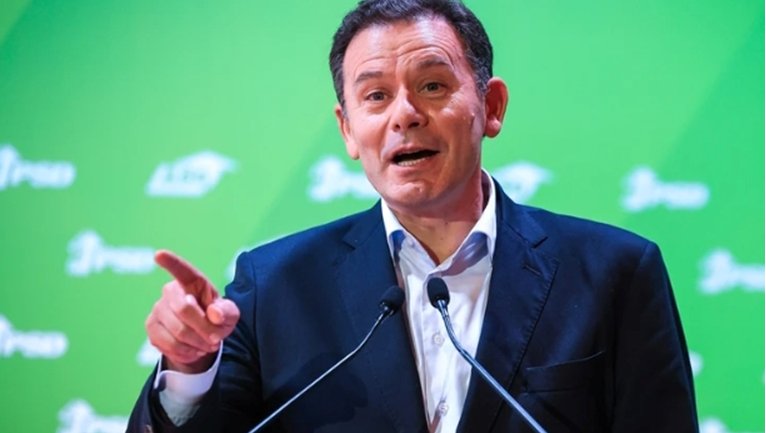 Candidato presidencial hablando en un evento con fondo verde