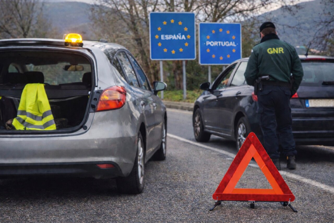 Vehículo detenido en la frontera entre España y Portugal con señal de advertencia.