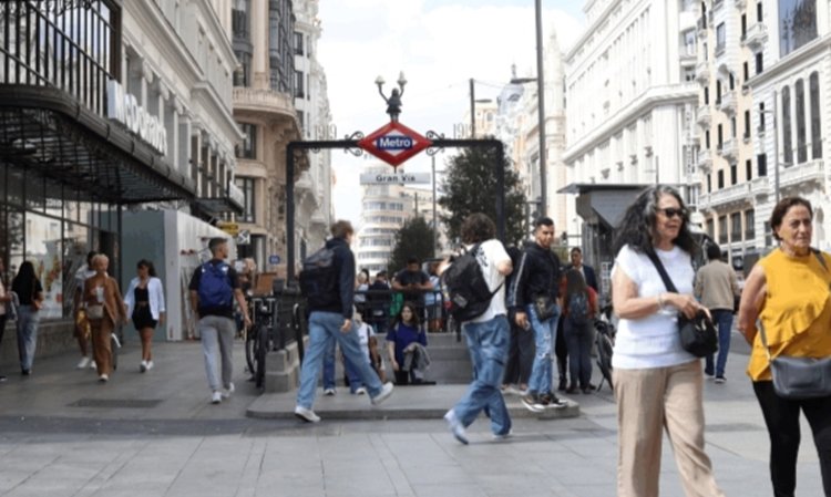 Vista de la Gran Vía en Madrid con personas caminando y estación de metro
