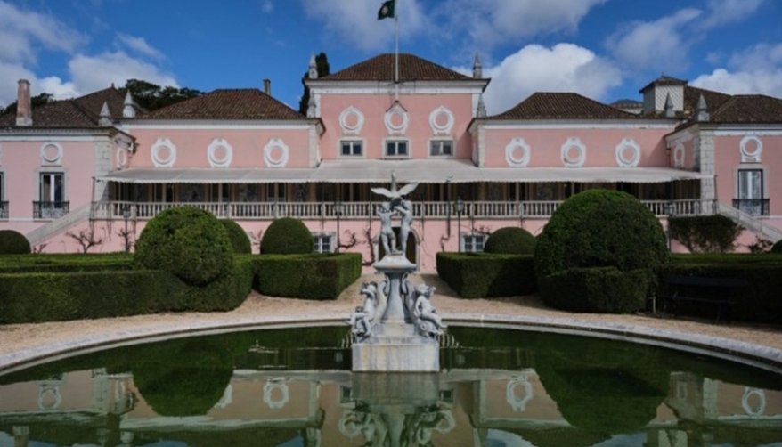 Vista de un lago con un palacio rosa y jardines en Portugal