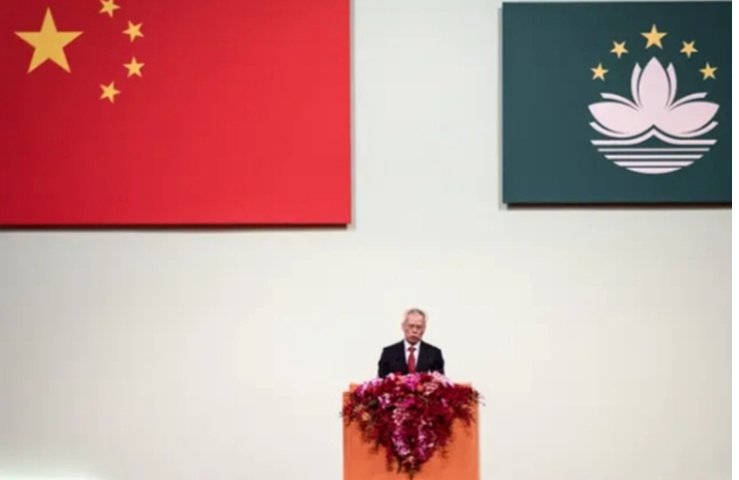 Líder de Macau hablando bajo banderas de China y Macau
