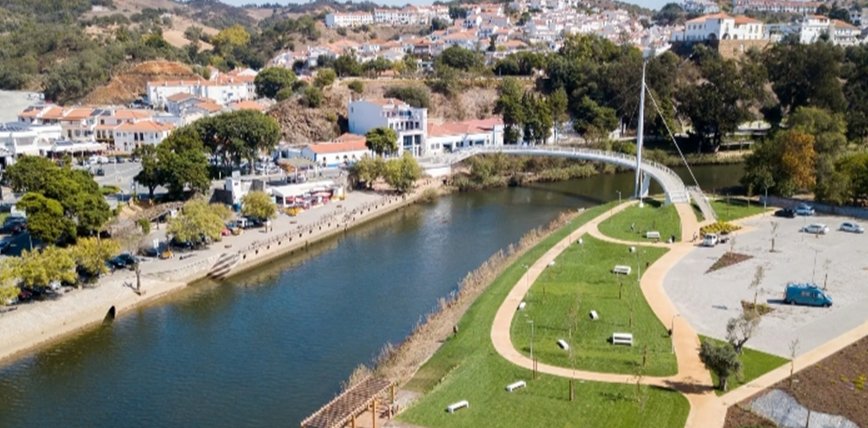 Vista aérea do rio em Odemira com áreas verdes e passeios.