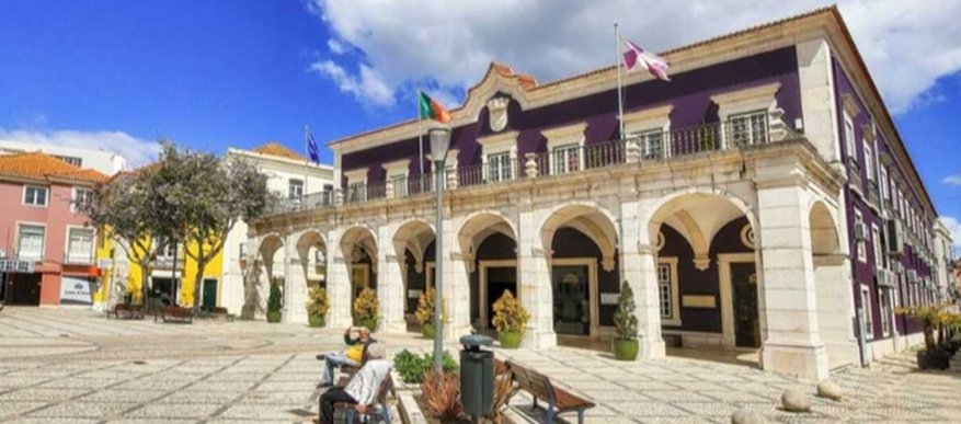 Fachada del municipio de Setúbal con banderas y bancos en la plaza