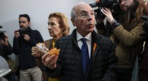 Candidato sosteniendo un pastel mientras es fotografiado por la prensa