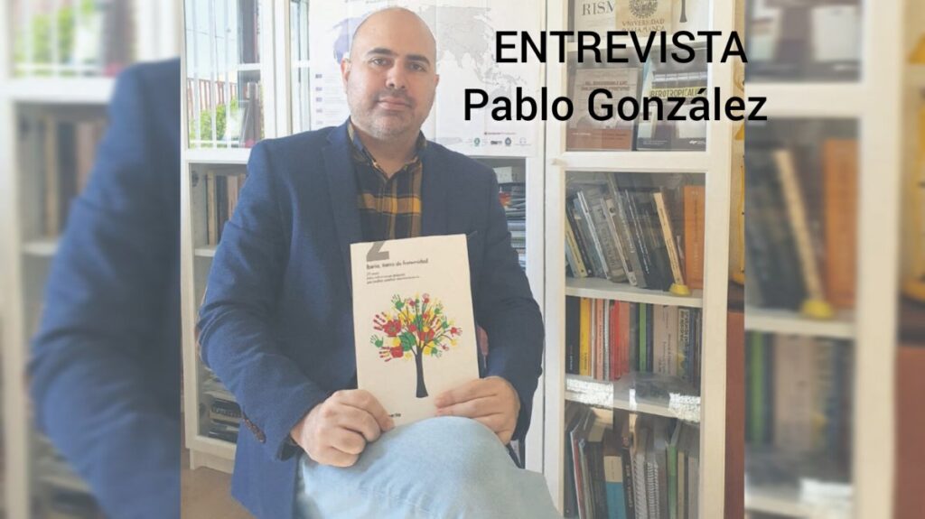 Pablo González Velasco sosteniendo un libro en una biblioteca