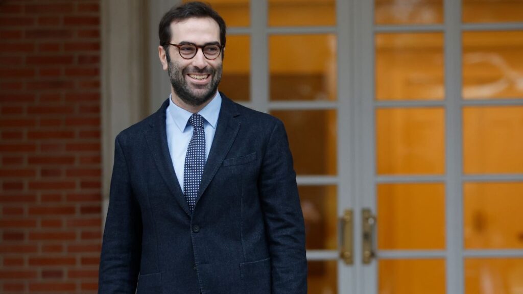 Ministro de Economía sonriendo frente a una puerta