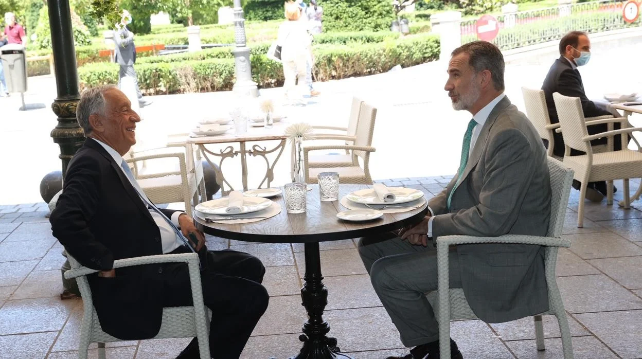 El presidente de Portugal y el rey de España conversando en una mesa.