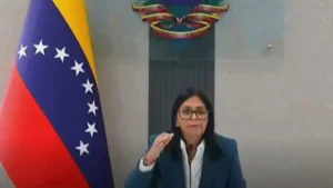 Delcy Rodríguez hablando frente a la bandera de Venezuela