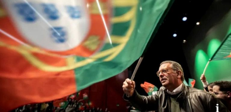 Hombre sosteniendo una bandera de Portugal durante un evento político