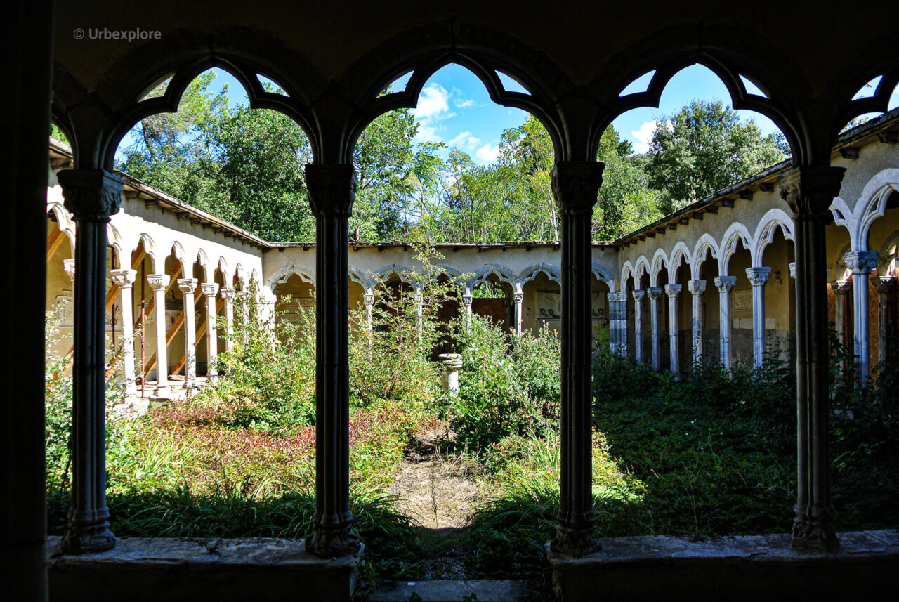 Vista de un patio abandonado con vegetación y arcos arquitectónicos.