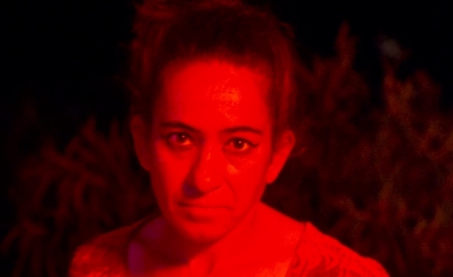 Mujer con expresión intensa en un entorno iluminado en rojo