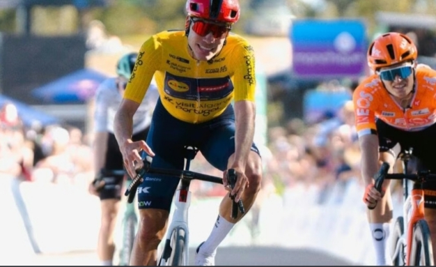 Juan Ayuso cruzando la meta en la Volta ao Algarve con la camiseta amarilla