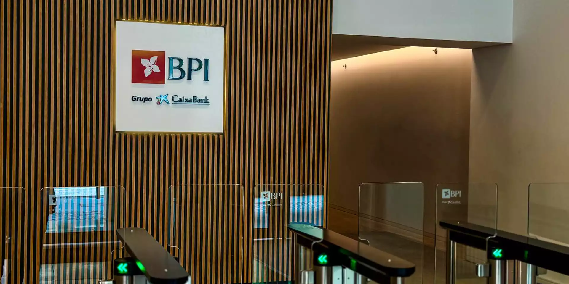 Interior de la oficina de BPI con logo de CaixaBank en la pared