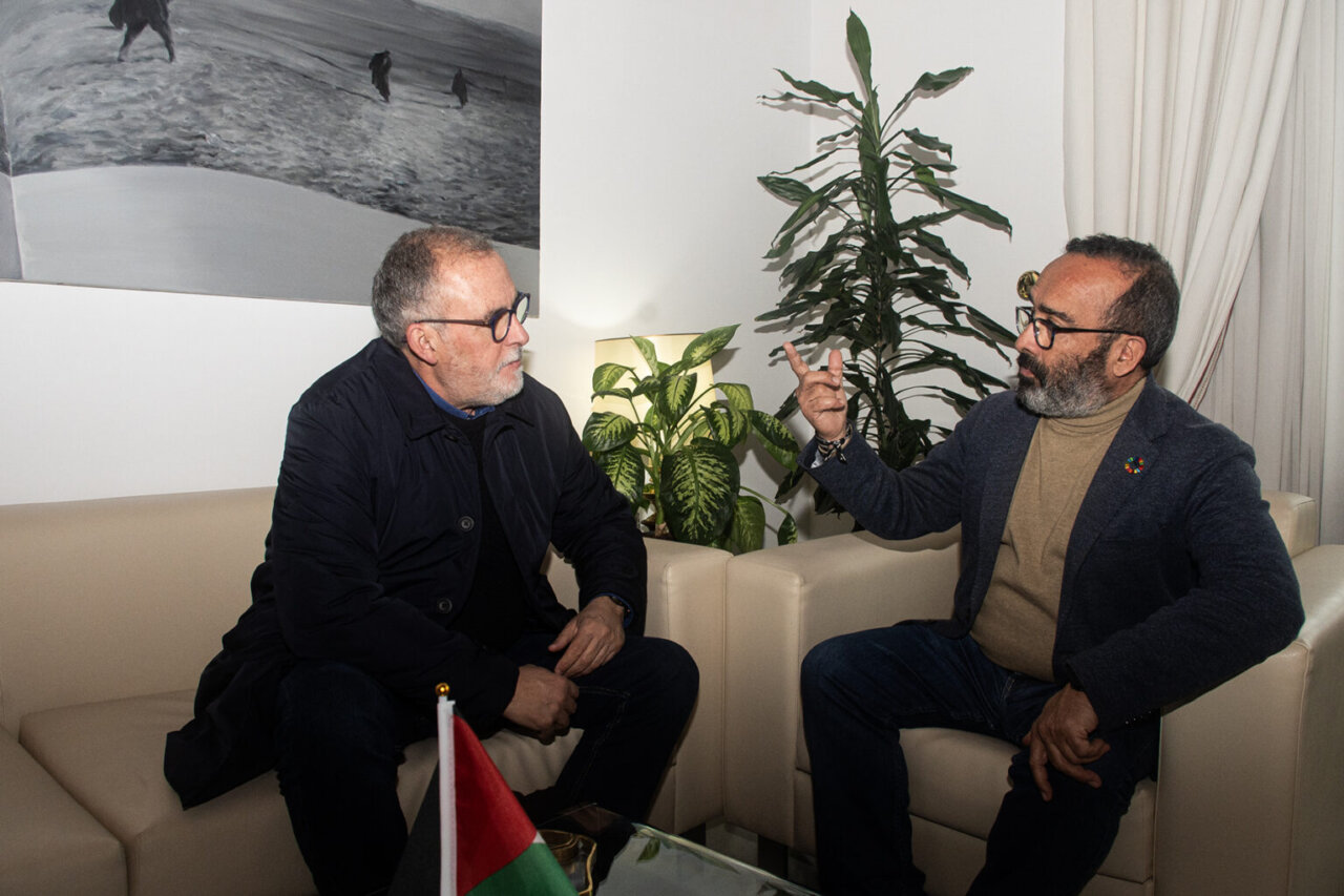 Dos hombres conversando en una reunión sobre turismo en Cáceres.
