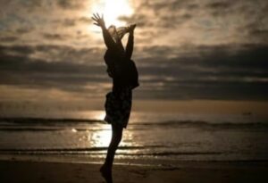 Silhouette of a person celebrating at the beach during sunset