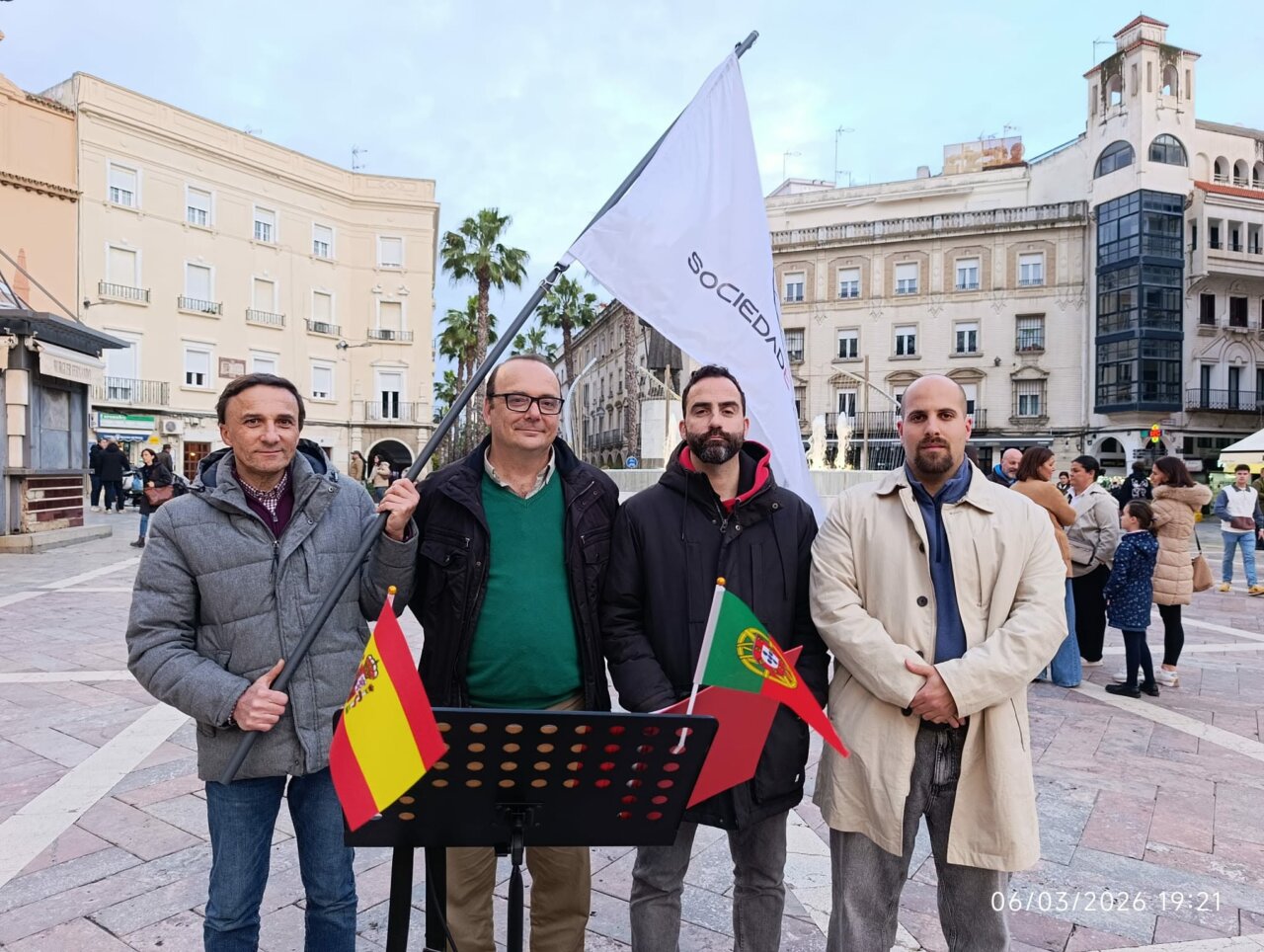 Cuatro hombres sosteniendo banderas de España y Portugal en una cumbre