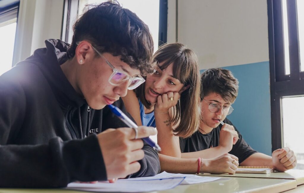 Tres estudiantes concentrados en un aula mientras estudian juntos.