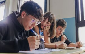 Tres estudiantes concentrados en un aula mientras estudian juntos.
