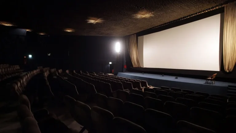 Interior de un cine vacío con una pantalla grande y asientos cómodos