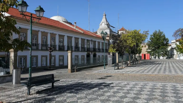 Vista de uma praça em Portalegre com edifícios históricos e árvores.