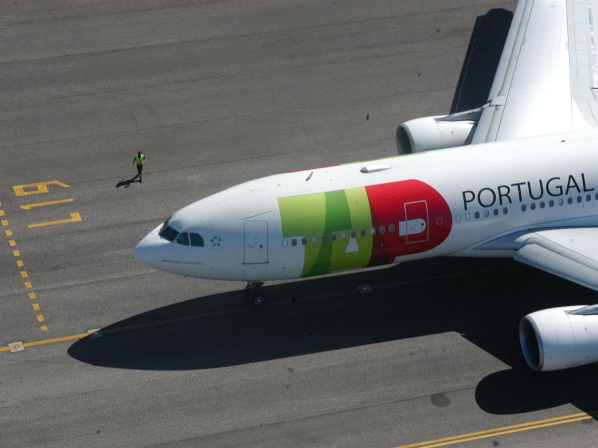 Avión de TAP Portugal en la pista con un trabajador cerca.