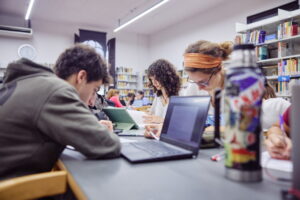Estudiantes trabajando en una biblioteca, mostrando concentración en sus tareas.