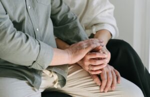 Manos de personas mayores entrelazadas en un contexto de apoyo emocional