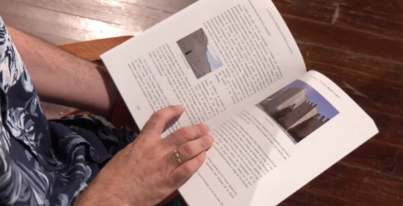 Persona sosteniendo un libro sobre castillos y fortificaciones en la frontera hispano-portuguesa