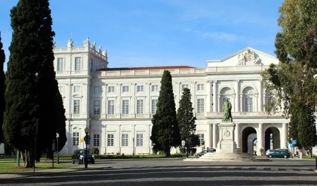 Vista exterior del Palacio Nacional de Ajuda en Lisboa con árboles y estatuas.