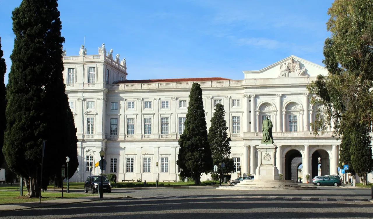 Vista exterior del Palacio Nacional de Ajuda en Lisboa con árboles y estatuas.