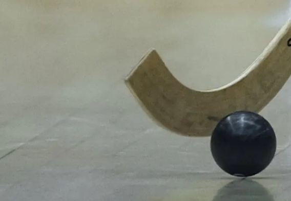 Stick de hóquei em patins e bola em movimento no chão