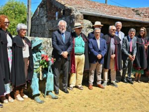 Acto en el Couto Mixto con figuras destacadas y una escultura