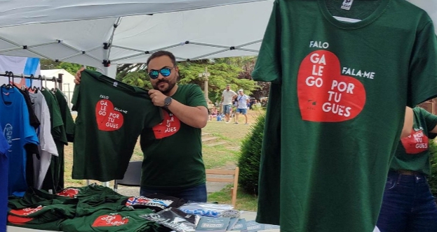 Hombre sosteniendo camisetas de la campaña Falo galego, fala-me português