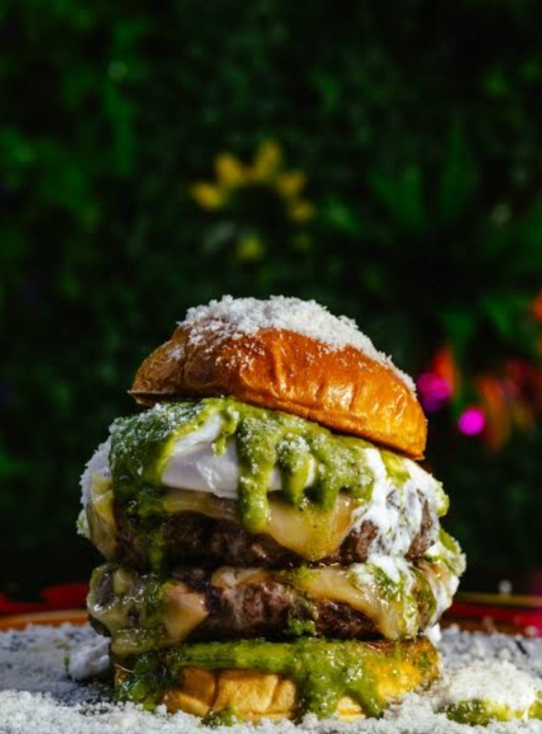 Hamburguesa apilada con salsa verde y queso derretido