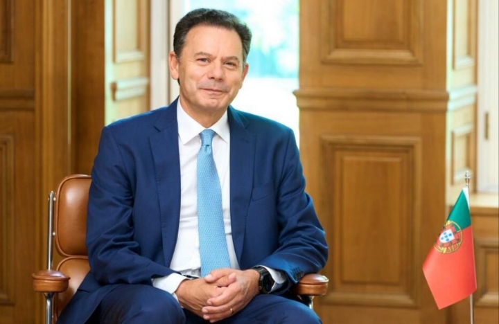 Luís Montenegro sentado en una silla con una bandera de Portugal.
