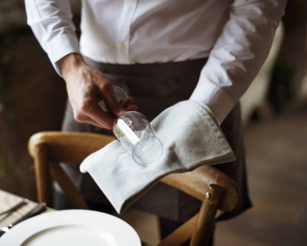 Un camarero limpiando una copa en un restaurante
