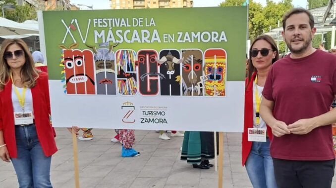 Participantes en el XV Festival de la Máscara en Zamora con un cartel colorido.