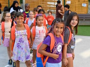 Niños con mochilas naranjas en un entorno escolar