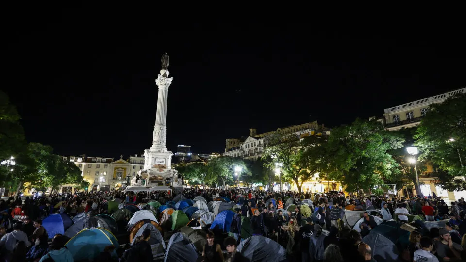 Personas y numerosas tiendas de campaña ocupan una plaza iluminada por la noche
