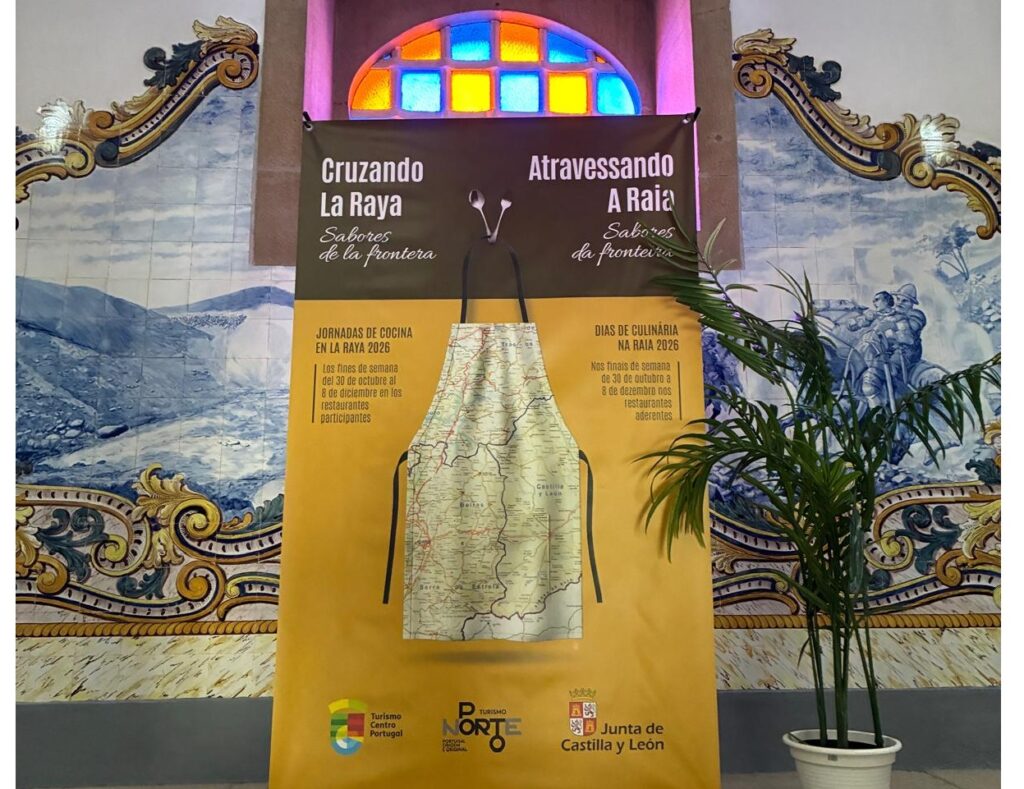 Cartel bilingüe de las jornadas gastronómicas Cruzando La Raya frente a azulejos decorativos
