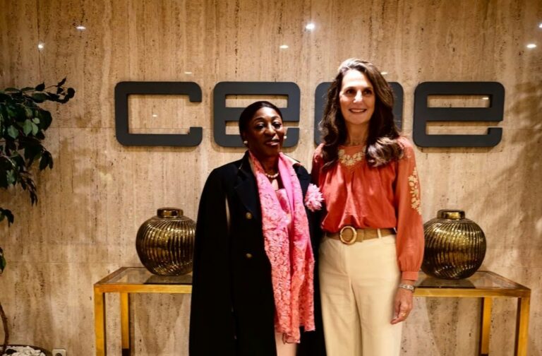 Dos mujeres posan frente al rótulo de CEOE en el interior de un edificio.