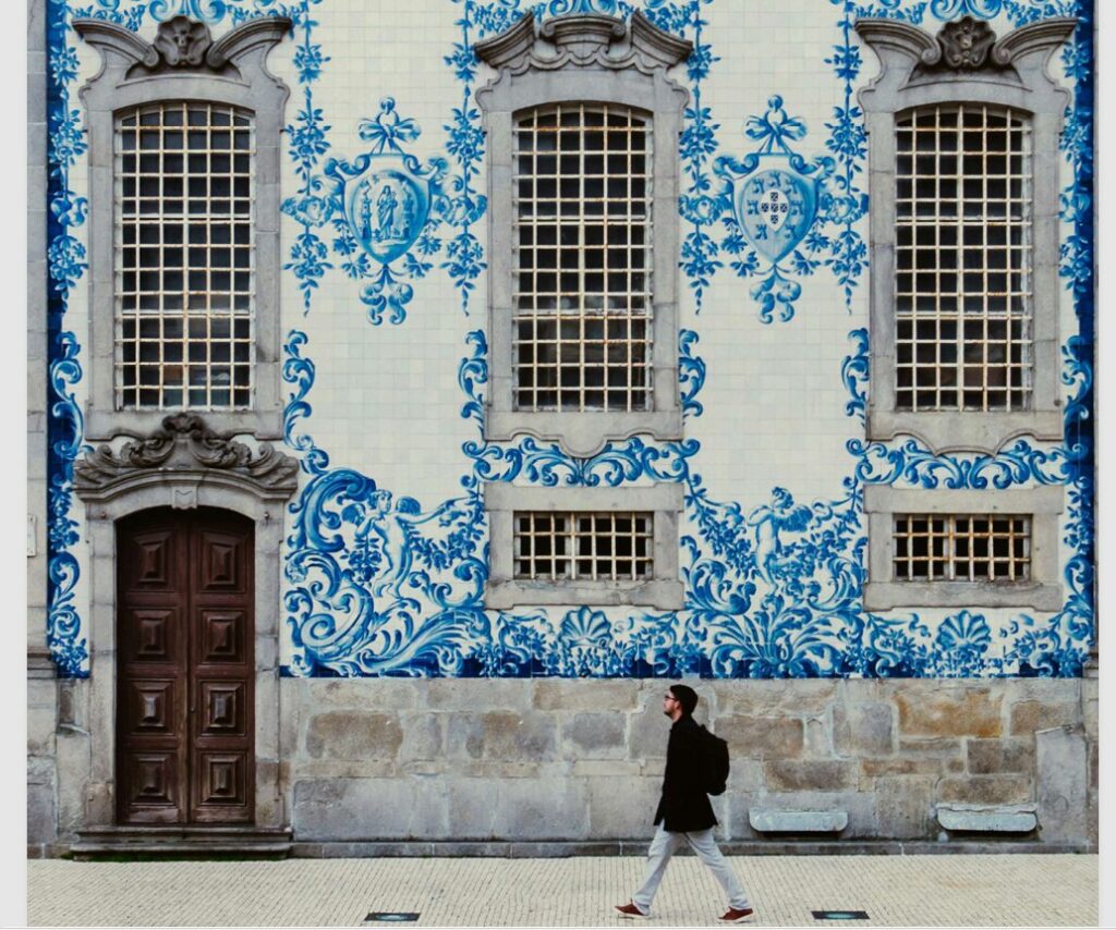 Fachada revestida de azulejos azules, con ventanas altas y una persona caminando.