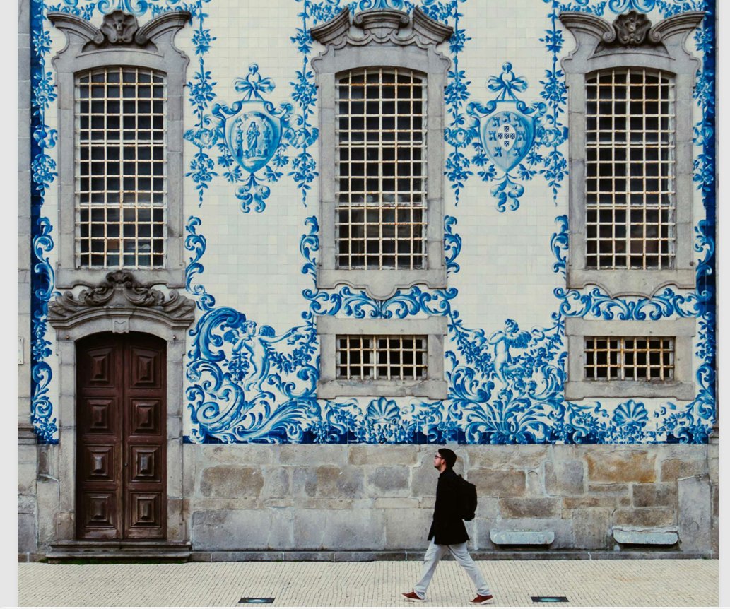 Fachada revestida de azulejos azules, con ventanas altas y una persona caminando.