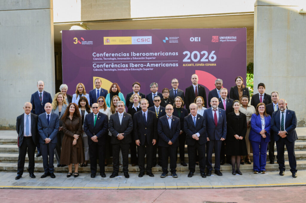 Grupo de asistentes posa ante el cartel de las Conferencias Iberoamericanas 2026 en Alicante.