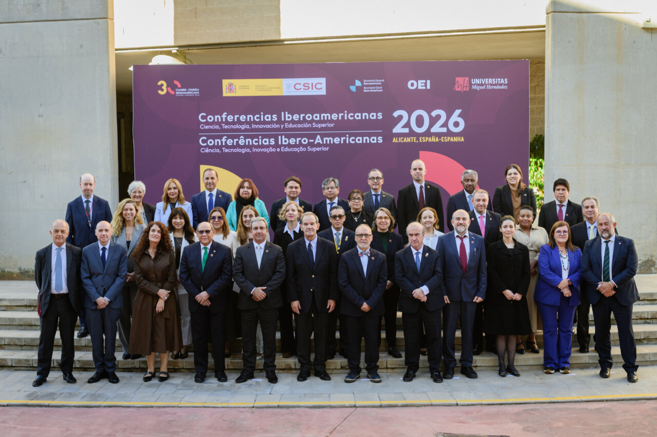 Grupo de asistentes posa ante el cartel de las Conferencias Iberoamericanas 2026 en Alicante.